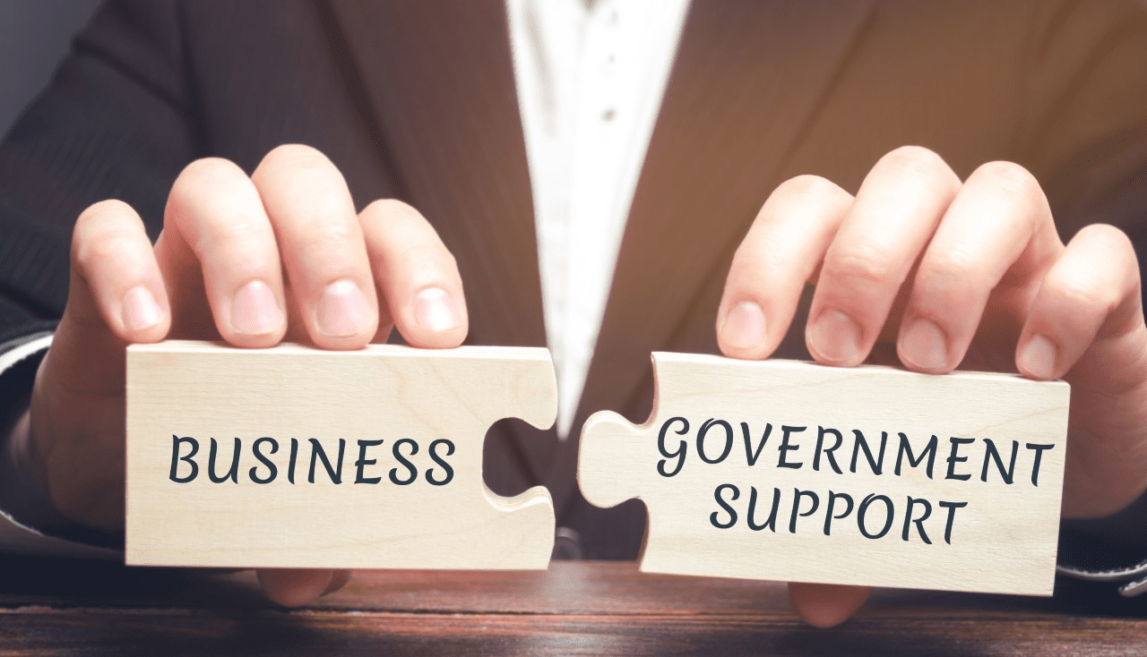 Two jigsaw pieces spelling 'business government support'