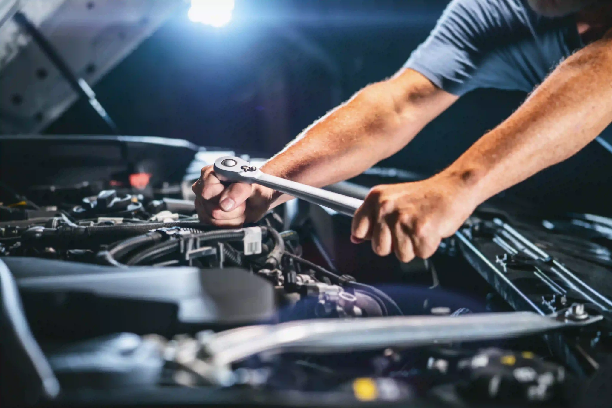 Close up of auto mechanic working on car engine in mechanics garage.