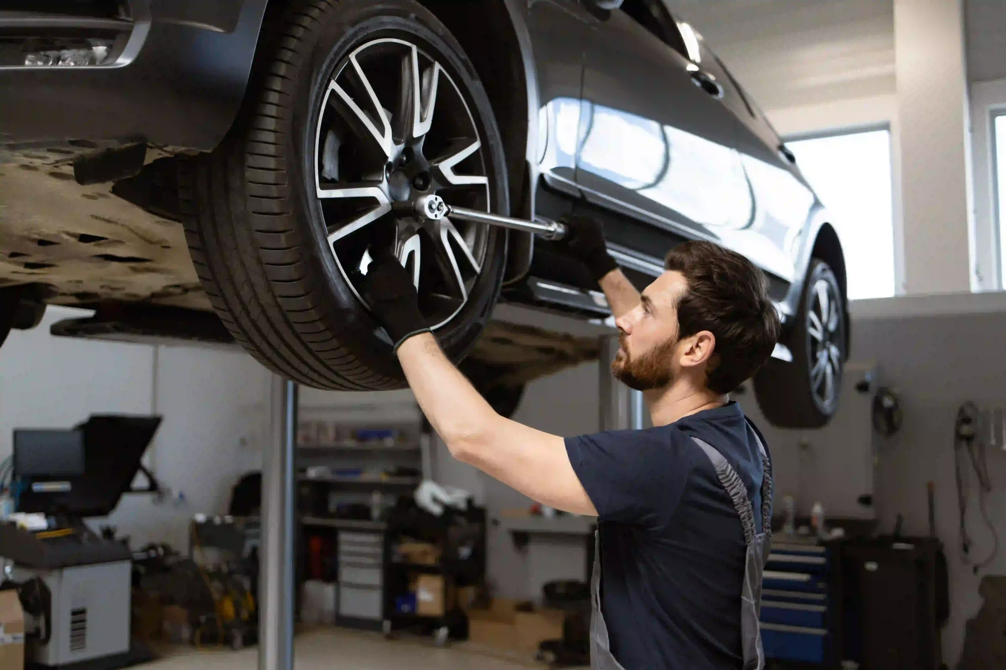 Professional auto service technician working with tools in garage. Vehicle maintenance and repair concept.