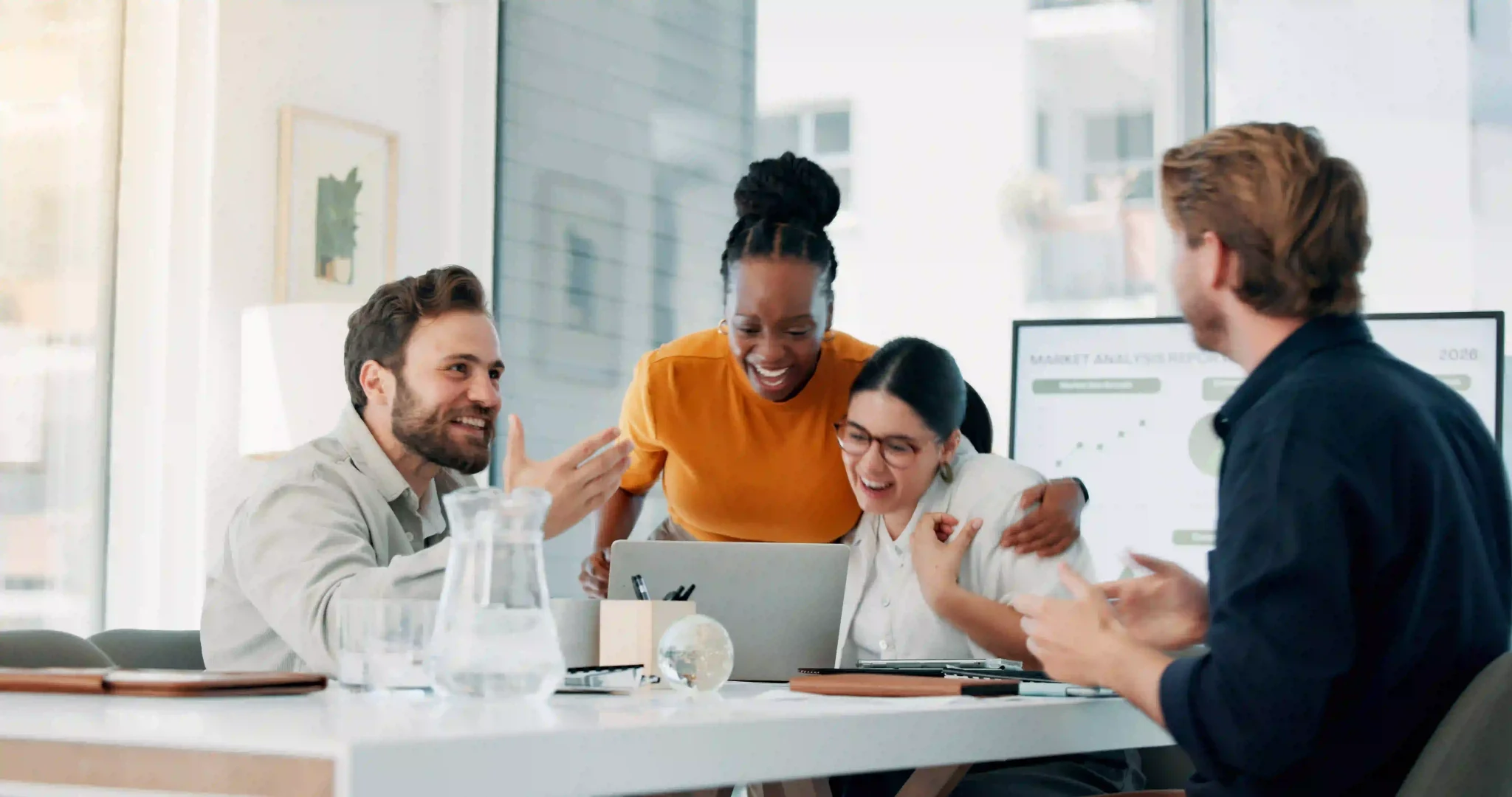 Team gathered around a laptop, smiling at the recent report.